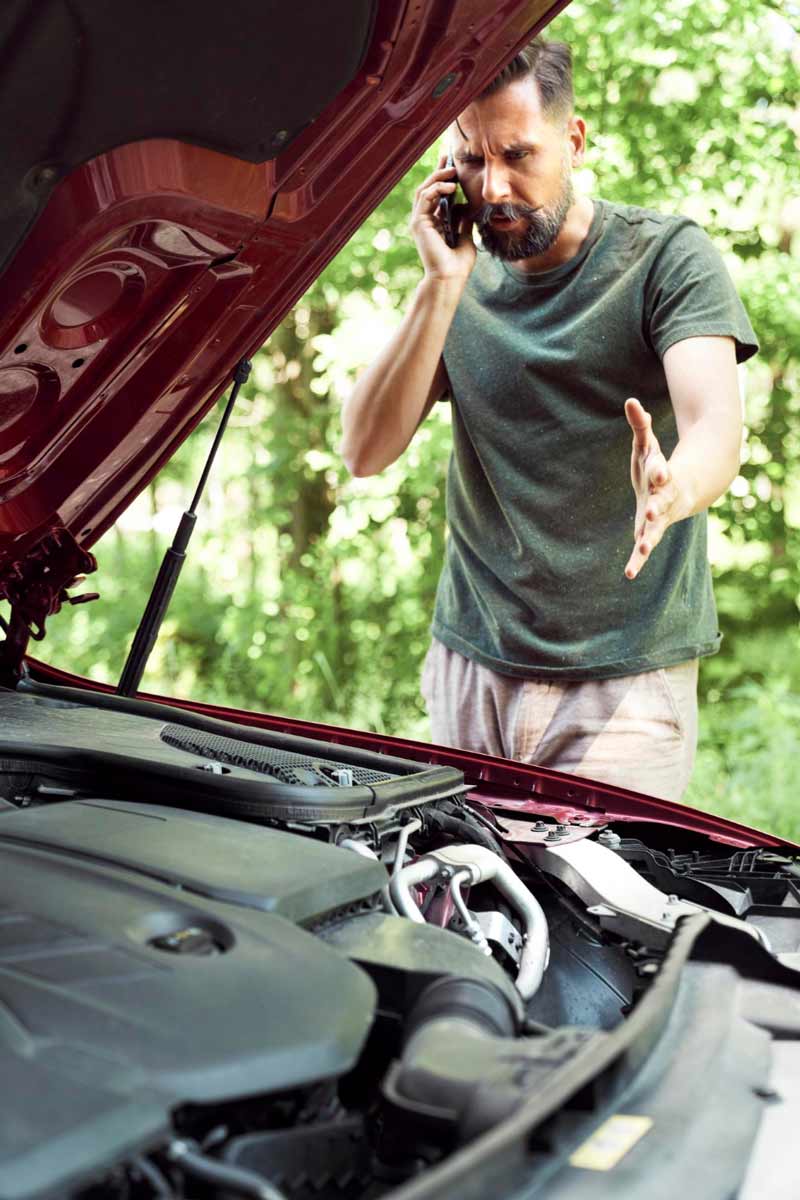 Junger Mann prüft Getriebeschaden bei Schrottauto Ankauf Olpe